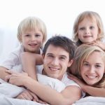 A family with two children on a bed in the bedroom